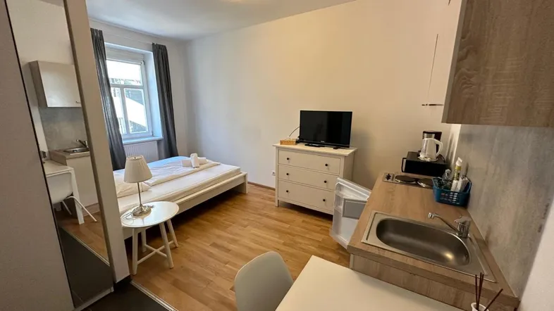 Gemütliches Studio-Apartment mit Schlafbereich, Fernseher und integrierter Küchenzeile, ideal für Einzelpersonen.