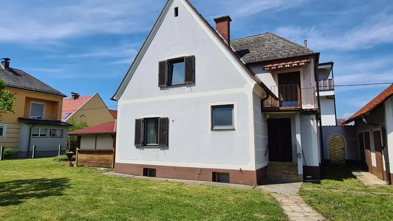Charmantes Einfamilienhaus mit Satteldach und kleinem Balkon, umgeben von einem grünen Garten.
