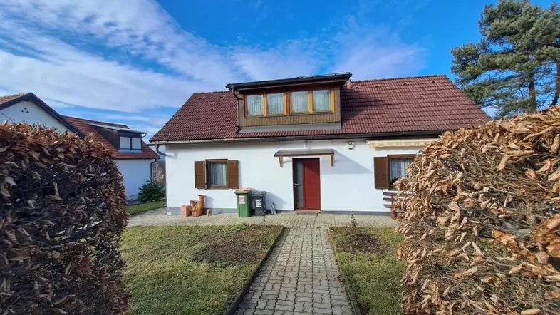 Vorderansicht eines Einfamilienhauses mit gepflegtem Vorgarten und blauer Himmel.