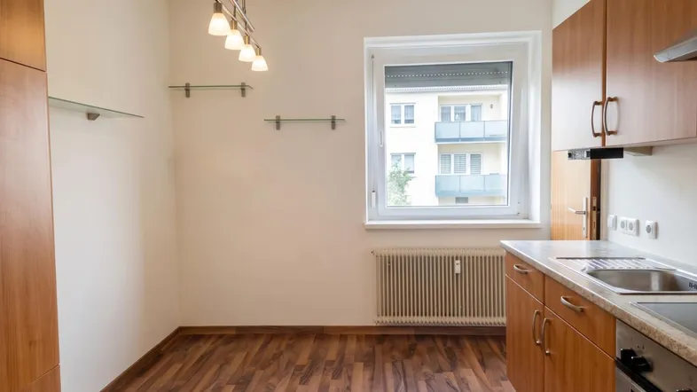 Helle Küche mit Holzschränken, Laminatboden und Blick auf die gegenüberliegenden Balkone.