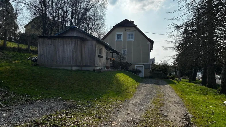 Einfahrt zum Haus mit einem Nebengebäude und viel Grünfläche in ländlicher Umgebung.