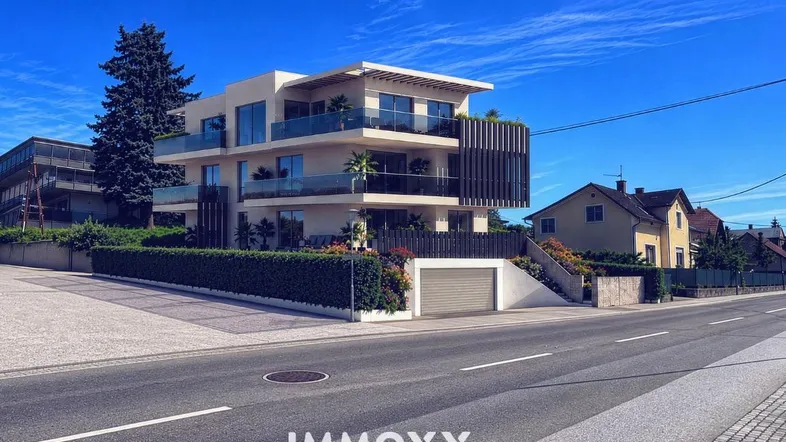 Moderne Wohnanlage mit mehreren Balkonen und Tiefgaragenzufahrt von der Straße aus.