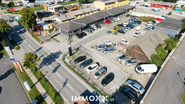 Luftaufnahme eines Gewerbegebiets mit mehreren Gebäuden, großem Parkplatz und umliegenden Straßen.