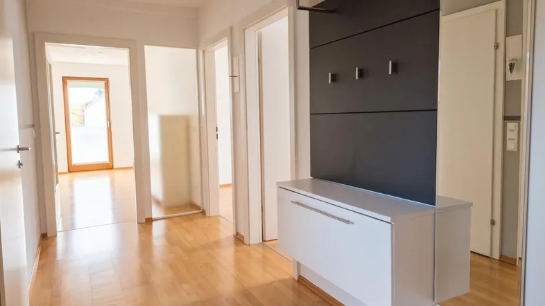 Heller Flur mit Parkettboden und moderner Garderobe, der zu weiteren Räumen führt.