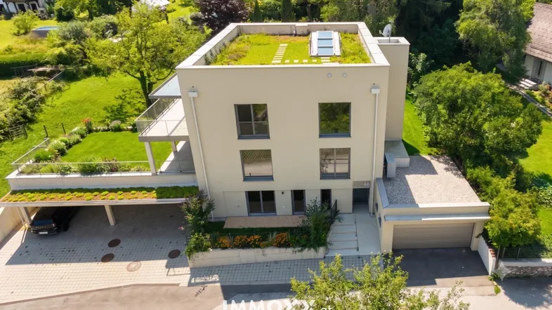 Moderne Architektur mit begrüntem Flachdach, Carport und Garage in grüner Umgebung.