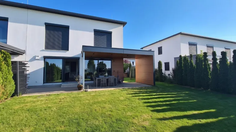 Modernes Haus mit großem Garten und überdachter Terrasse, ideal für Entspannung im Freien.