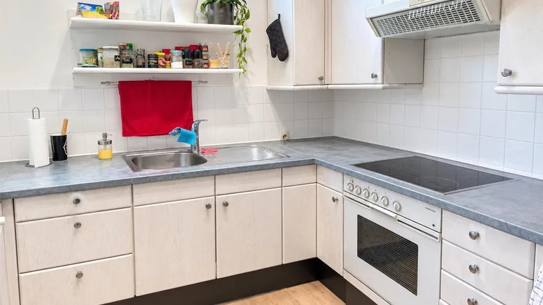 Helle Küche mit weißen Schränken, Fliesenrückwand und integriertem Kochfeld.