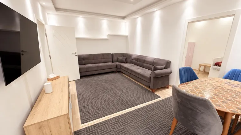 Heller Wohn- und Essbereich mit modernem Sofa, Esstisch und indirekter Deckenbeleuchtung.