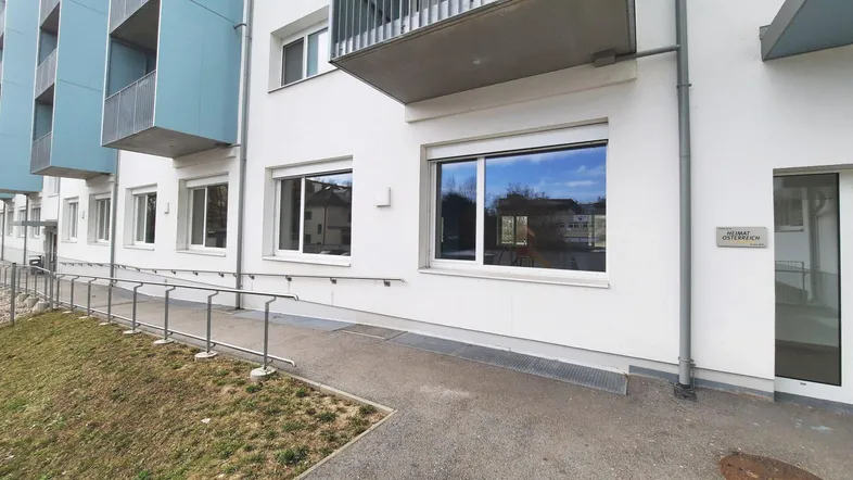 Moderne Gebäudefassade mit barrierefreiem Zugang über eine Rampe und Balkonen in den oberen Etagen.