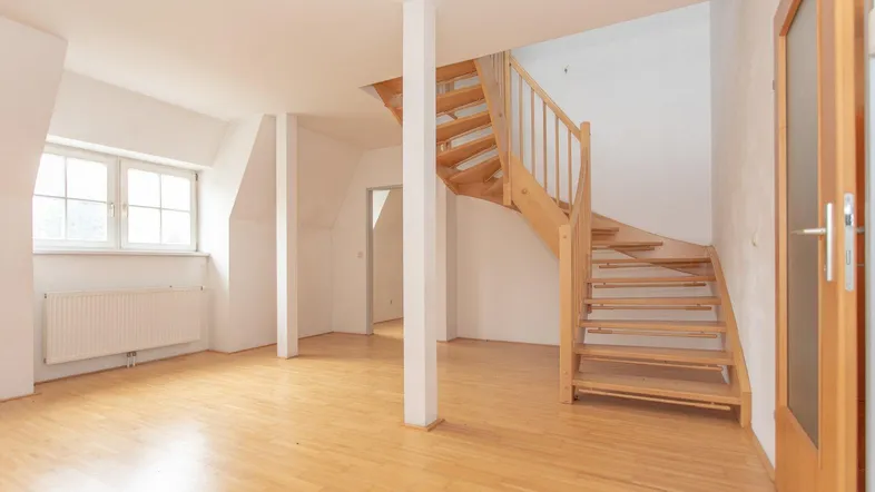Heller Wohnbereich mit Holztreppe und Parkettboden, ideal für individuelle Gestaltung und vielseitige Nutzung.
