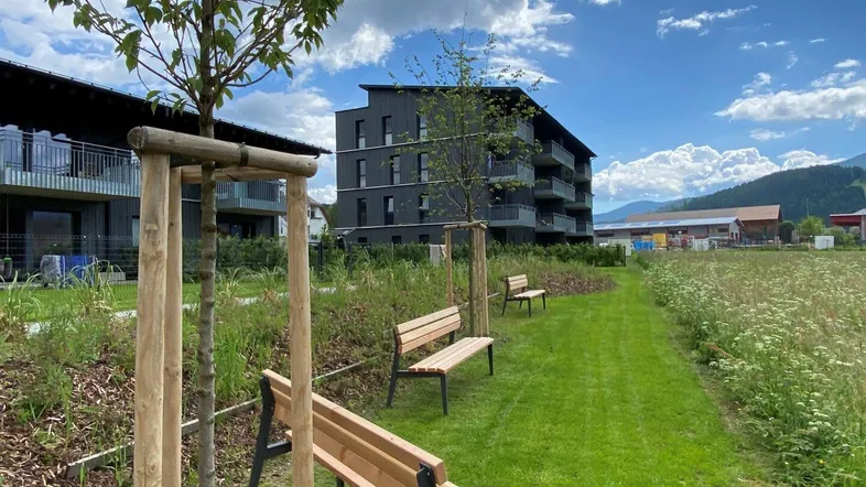 Moderne Wohnanlage mit Sitzbänken im Grünen und Blick auf die umliegende Natur.