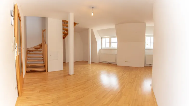 Helles, offenes Wohnzimmer mit Parkettboden und Holztreppe, das vielseitige Gestaltungsmöglichkeiten bietet.