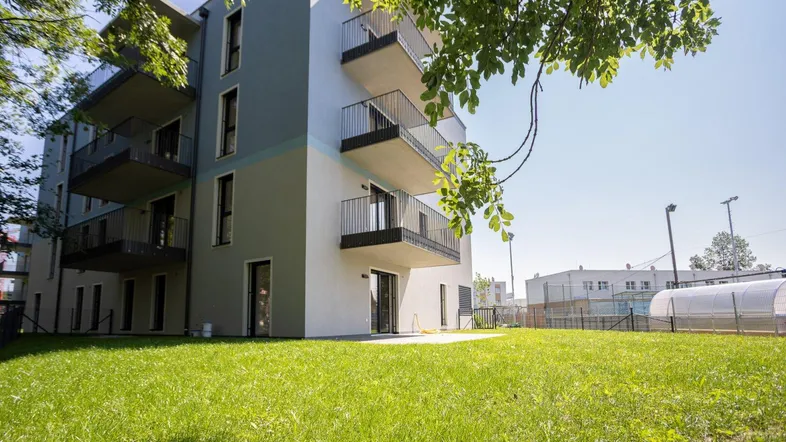 Modernes Mehrfamilienhaus mit Balkonen und einer gepflegten Rasenfläche im Vordergrund.
