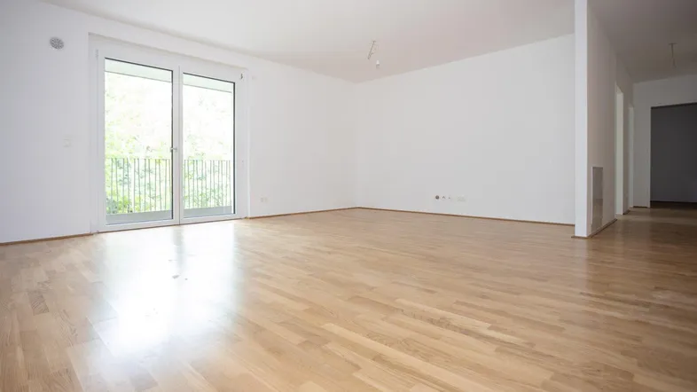 Helles Wohnzimmer mit Parkettboden und Zugang zu einem Balkon, bereit zur individuellen Gestaltung.