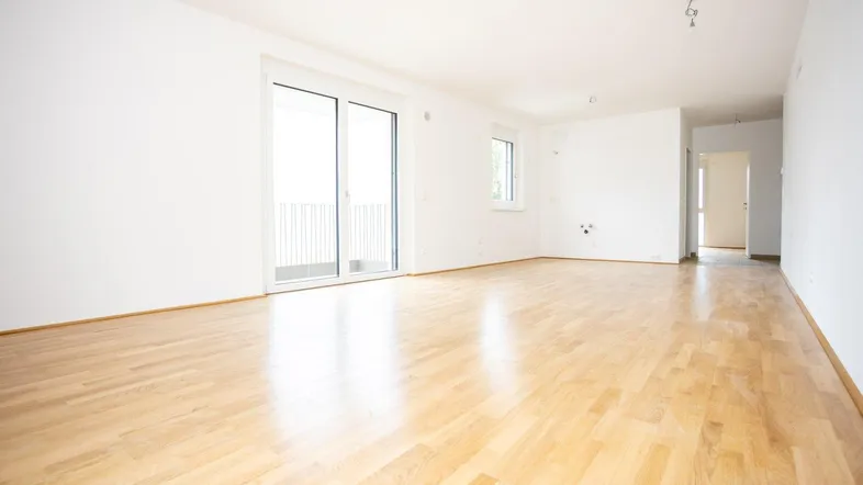 Lichtdurchfluteter Wohnbereich mit Holzboden und Schiebetür zum Außenbereich.