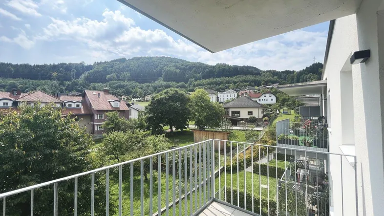Geräumiger Balkon mit Fliesenboden und weitem Blick über die umliegende Landschaft und grüne Hügel.