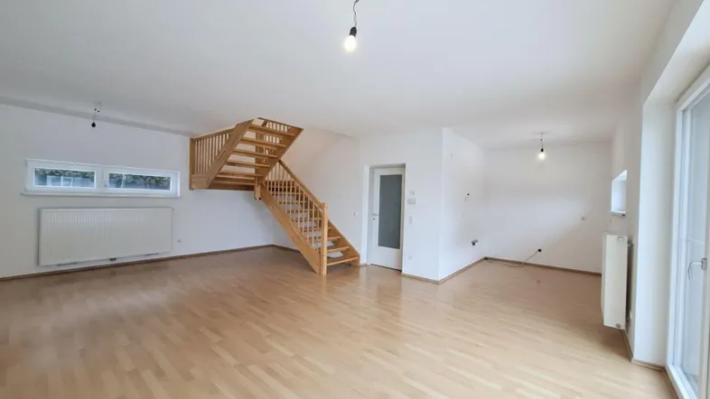 Helles, geräumiges Wohnzimmer mit Holztreppe und Parkettboden, bereit zur individuellen Gestaltung.