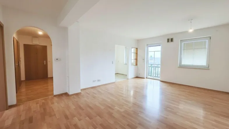 Geräumiges Wohnzimmer mit hellem Parkettboden und Zugang zu einem Balkon, ideal für entspannte Stunden.