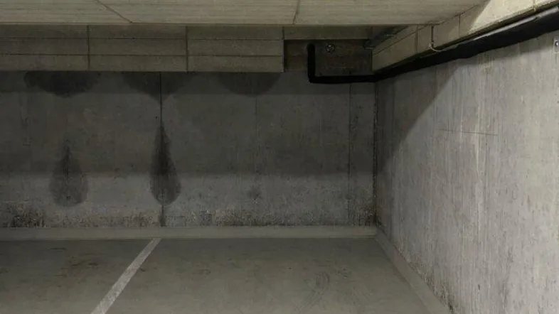 Leerer Parkplatz in einer Tiefgarage mit Betonwänden und -decke, gekennzeichnet durch eine weiße Linie.