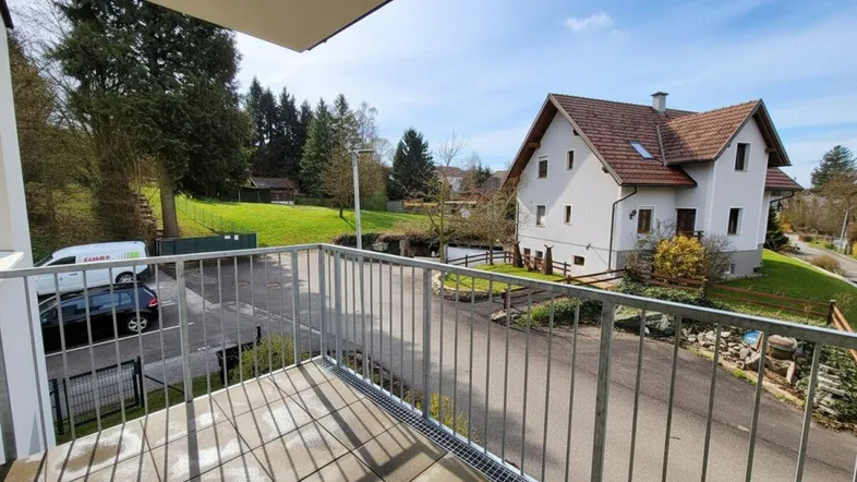 Balkon mit Fliesenboden und Metallgeländer bietet einen weiten Blick auf die umliegende Wohngegend und viel Grün.