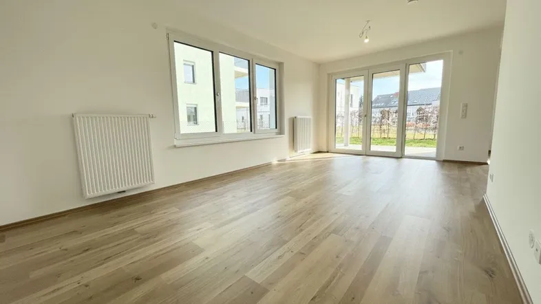 Helles Zimmer mit Laminatboden und Zugang zur Terrasse, ideal als Wohnbereich nutzbar.