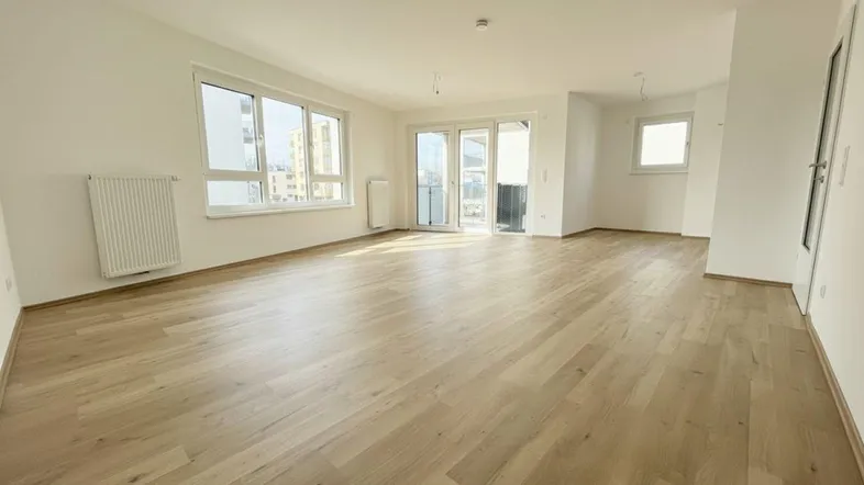 Helles und geräumiges Wohnzimmer mit neuem Laminatboden und Zugang zum Balkon.