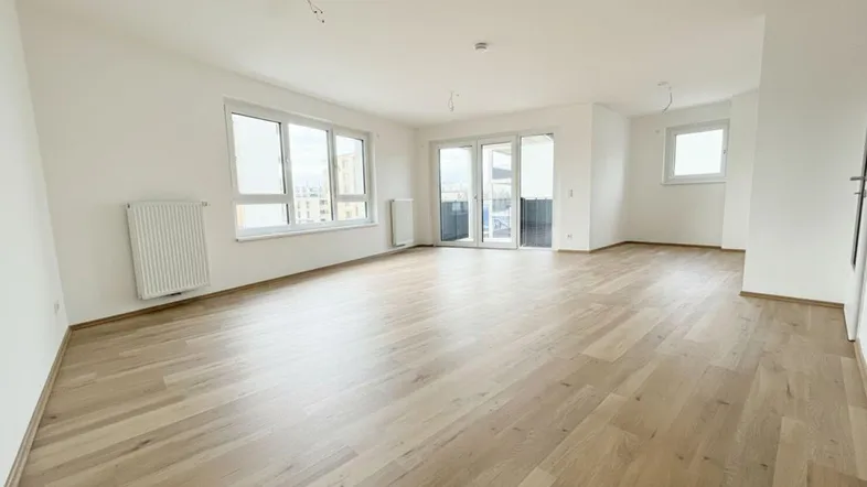 Helles Wohnzimmer mit neuem Parkettboden, großen Fenstern und direktem Zugang zum Balkon.