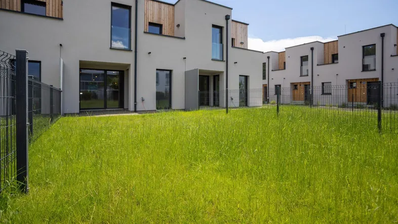 Moderne Reihenhäuser mit schlichter Architektur und einer großen Rasenfläche im Vordergrund.