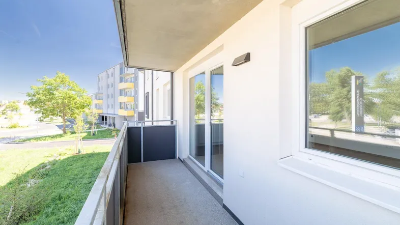 Heller Balkon mit Blick ins Grüne und auf die umliegende Wohnbebauung eines Neubaus.