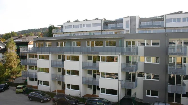 Modernes Mehrfamilienhaus mit Balkonen, großen Fenstern und Solaranlage auf dem Dach.