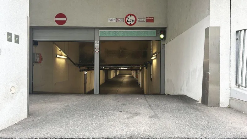 Einfahrt zu einer Tiefgarage mit Höhenbegrenzung von 2,05 Metern und Hinweisschildern.