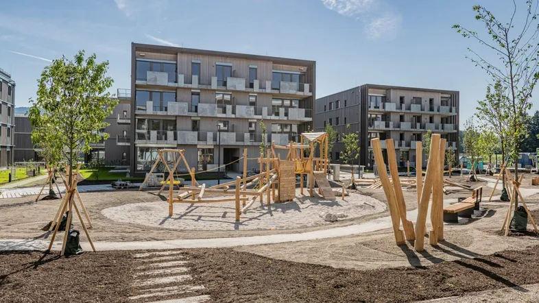 Moderner Wohnkomplex mit großem Kinderspielplatz und neuen Gebäuden unter blauem Himmel.