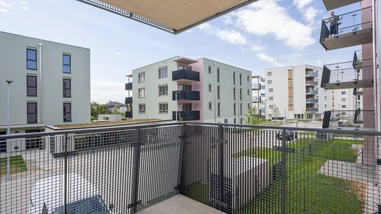 Blick vom Balkon auf die umliegenden modernen Wohngebäude und gepflegten Grünflächen.