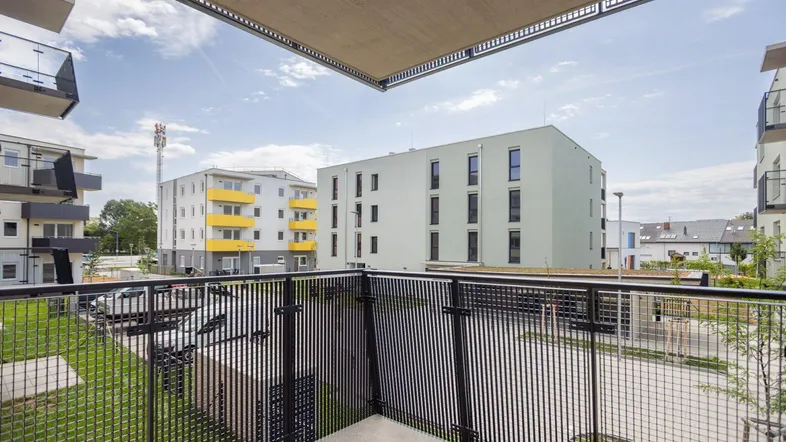 Geräumiger Balkon mit Blick auf die umliegenden Neubauten und den begrünten Innenhof.