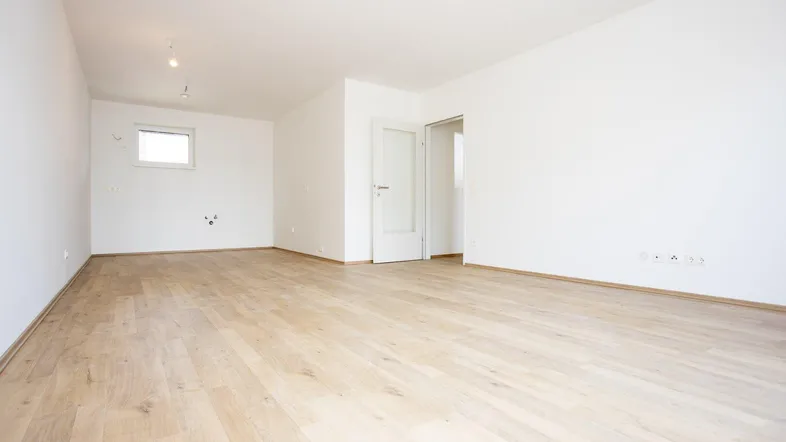 Heller, leerer Raum mit modernem Laminatboden und weißen Wänden, bereit zur individuellen Gestaltung.