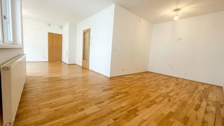 Helles Wohnzimmer mit neuwertigem Parkettboden und weißen Wänden, bereit zur individuellen Gestaltung.