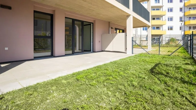 Große gepflasterte Terrasse mit direktem Zugang zum Garten und Blick auf das moderne Gebäude.