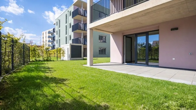 Erdgeschosswohnung mit privater Terrasse und Rasenfläche in einer modernen Wohnanlage.