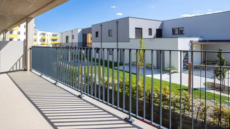 Geräumiger Balkon mit Blick auf den begrünten Innenhof und moderne Wohngebäude.