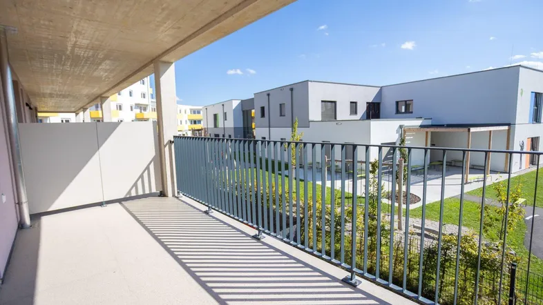 Geräumiger Balkon mit Blick auf die moderne Wohnanlage und grüne Außenbereiche.