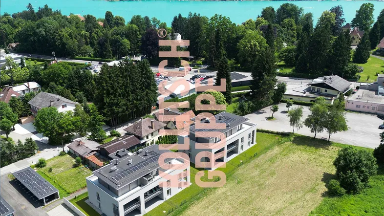 Luftaufnahme von modernen Wohngebäuden mit Blick auf einen See und grüne Umgebung.