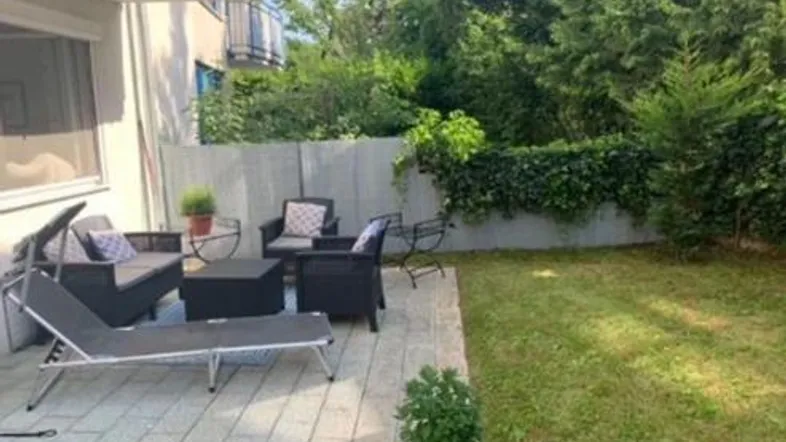 Möblierte Terrasse mit Liegestuhl und direktem Zugang zum gepflegten Rasengarten.
