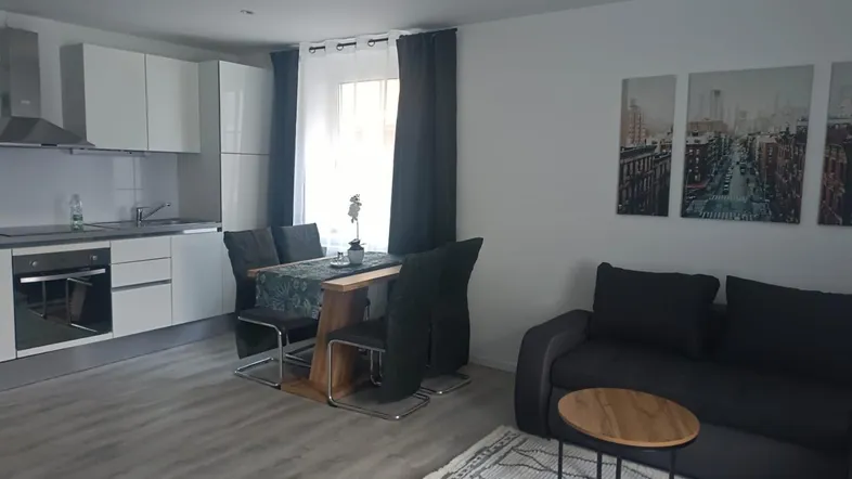 Heller offener Wohnbereich mit integrierter Küche, Esstisch und Sofa in modernem Stil.