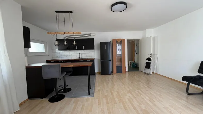 Offener Wohnbereich mit integrierter Küche, Holzboden und viel Tageslicht.