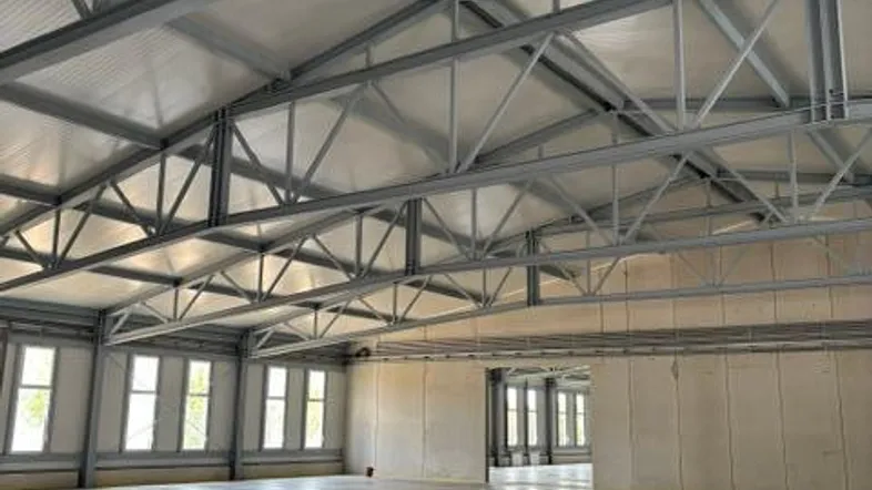 Große, helle Industriehalle mit sichtbaren Stahlträgern und poliertem Betonboden, ideal für Lager oder Produktion.