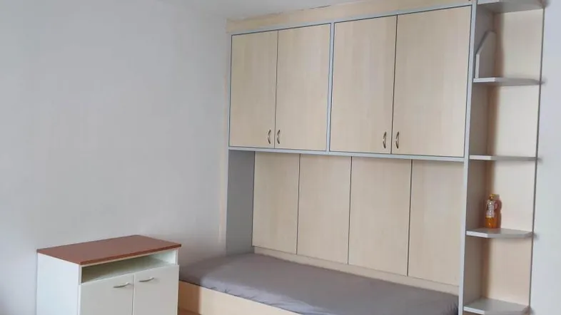 Helles Zimmer mit integriertem Bett und vielen Einbauschränken, ideal als Gäste- oder Jugendzimmer.