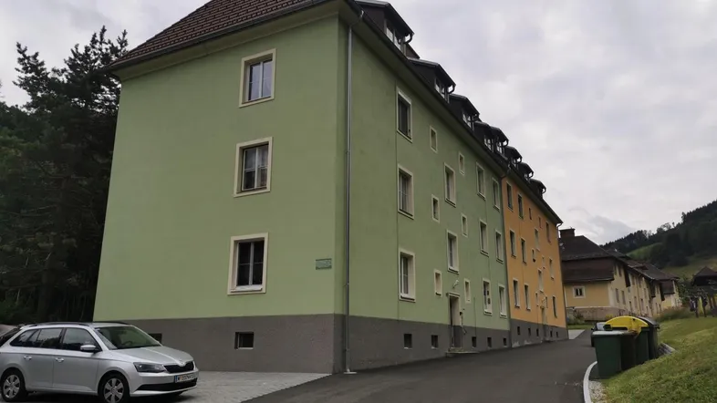 Mehrfamilienhaus mit hellgrüner Fassade und Satteldach in ländlicher Umgebung.