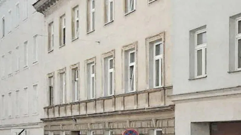 Altes Gebäude mit klassischer Fassade und vielen Fenstern an einer städtischen Straße.