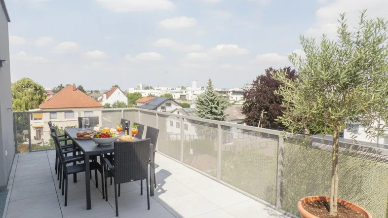 Große Dachterrasse mit Esstisch, Sitzgelegenheiten und weitem Blick über die Stadt.
