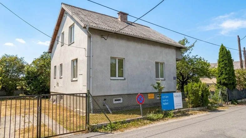 Einfamilienhaus von der Straße aus gesehen mit einfacher Fassade und Satteldach.